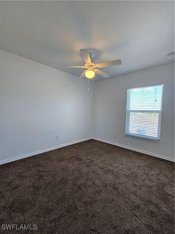 7027 Palpano Cir, Labelle, FL 33935 - empty room with dark carpet, baseboards, and a ceiling fan