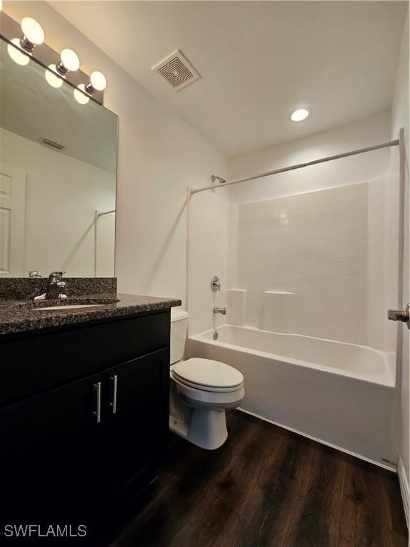 7027 Palpano Cir, Labelle, FL 33935 - full bathroom with tub / shower combination, vanity, visible vents, toilet, and wood finished floors
