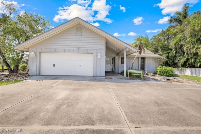 single story home featuring board and batten siding, driveway, a garage, and fence