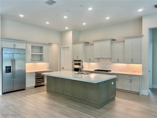 9499 Caymas Way, Naples, FL 34114 - kitchen with stainless steel appliances, wine cooler, backsplash, open shelves, and a center island with sink