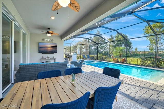 pool with outdoor lounge area, a ceiling fan, a patio, and glass enclosure