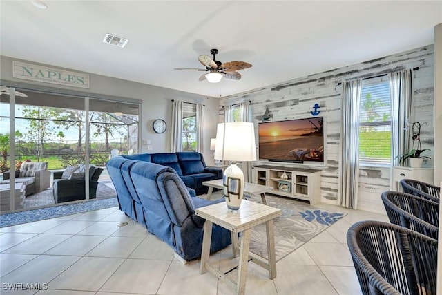 living area featuring light tile patterned flooring, an accent wall, ceiling fan, and visible vents