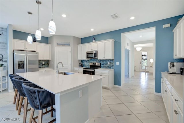 kitchen with appliances with stainless steel finishes, a sink, backsplash, and visible vents