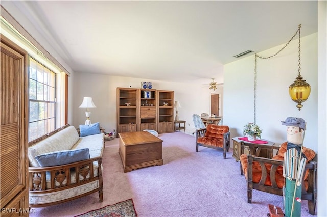 carpeted living area featuring visible vents and a ceiling fan