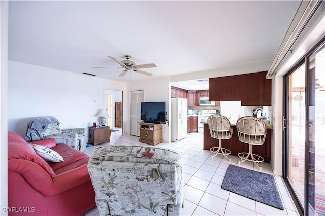 living area featuring light tile patterned flooring, a ceiling fan, and visible vents
