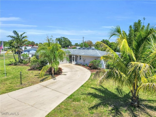 1514 Canal St, Lehigh Acres, FL 33936 - view of front of house featuring stucco siding, a front yard, and curved driveway