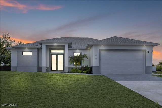 1819 NW 19th Ave, Cape Coral, FL 33993 - prairie-style home featuring driveway, a lawn, an attached garage, stucco siding, and french doors