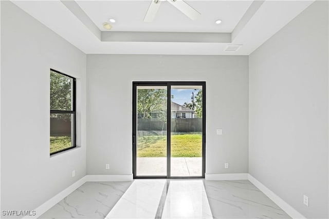 1819 NW 19th Ave, Cape Coral, FL 33993 - spare room with marble finish floor, a ceiling fan, a tray ceiling, and baseboards