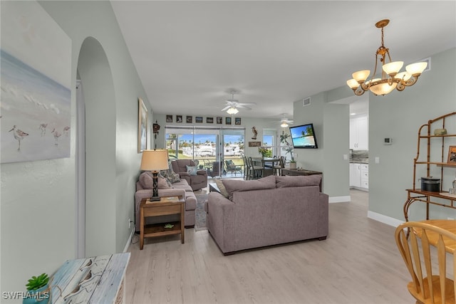 317 Sunrise Cay Unit 1-102, Naples, FL 34114 - living area with visible vents, baseboards, arched walkways, light wood-type flooring, and ceiling fan with notable chandelier