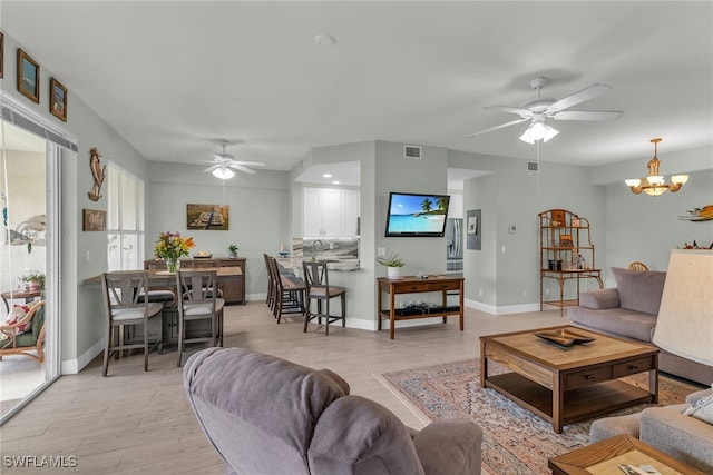 317 Sunrise Cay Unit 1-102, Naples, FL 34114 - living room featuring light wood-style floors, ceiling fan with notable chandelier, and baseboards