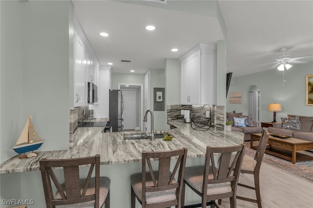 317 Sunrise Cay Unit 1-102, Naples, FL 34114 - kitchen featuring a peninsula, white cabinetry, light stone countertops, appliances with stainless steel finishes, and a sink