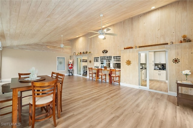 dining space with light wood-type flooring, wooden walls, a ceiling fan, high vaulted ceiling, and wooden ceiling