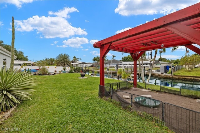 view of yard with a water view, fence, and a dock