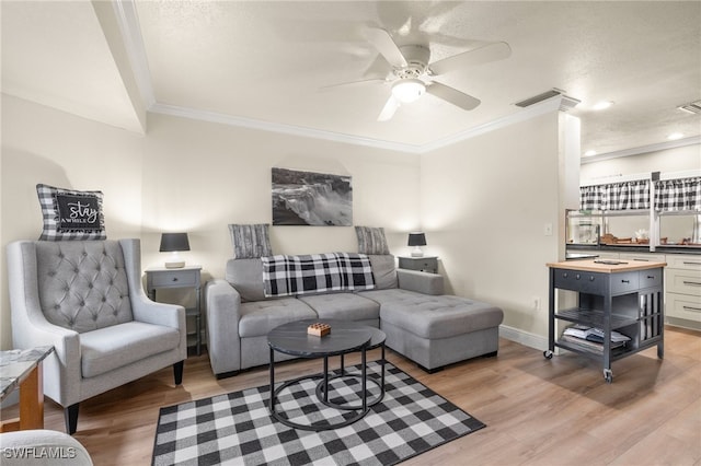 living area with light wood-style flooring, crown molding, ceiling fan, and visible vents