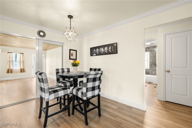 dining area with light wood-style flooring, baseboards, and crown molding