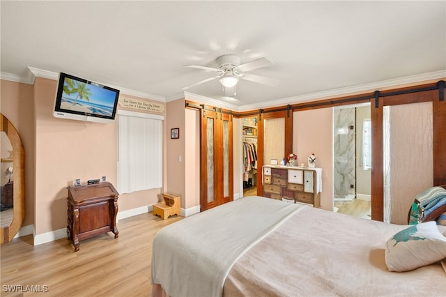 bedroom with a barn door, light wood-style floors, baseboards, and crown molding