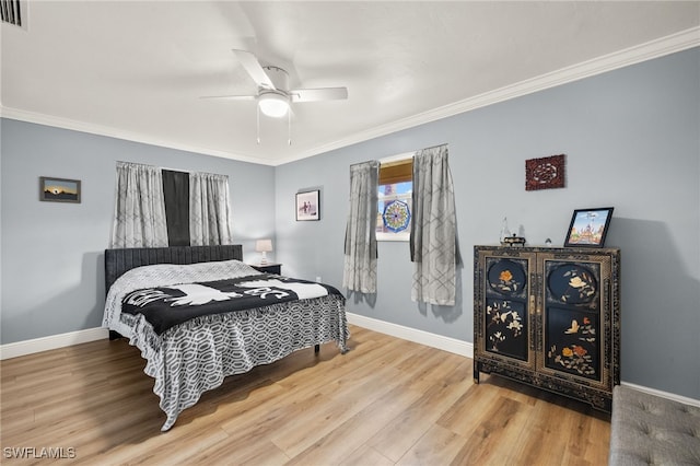 bedroom with a ceiling fan, ornamental molding, visible vents, wood finished floors, and baseboards
