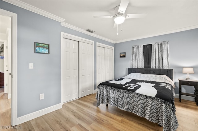 bedroom with baseboards, crown molding, visible vents, multiple closets, and wood finished floors