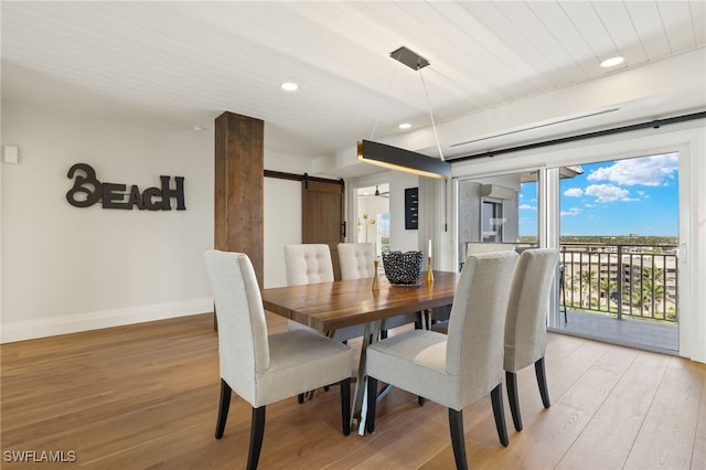 dining space featuring recessed lighting, a barn door, light wood-style flooring, and baseboards