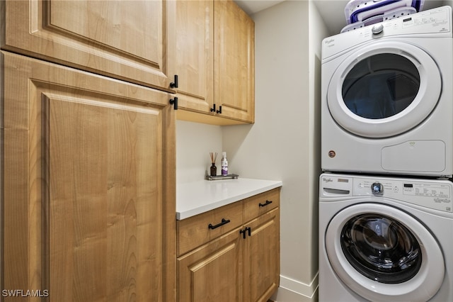 clothes washing area with stacked washer and dryer and cabinet space