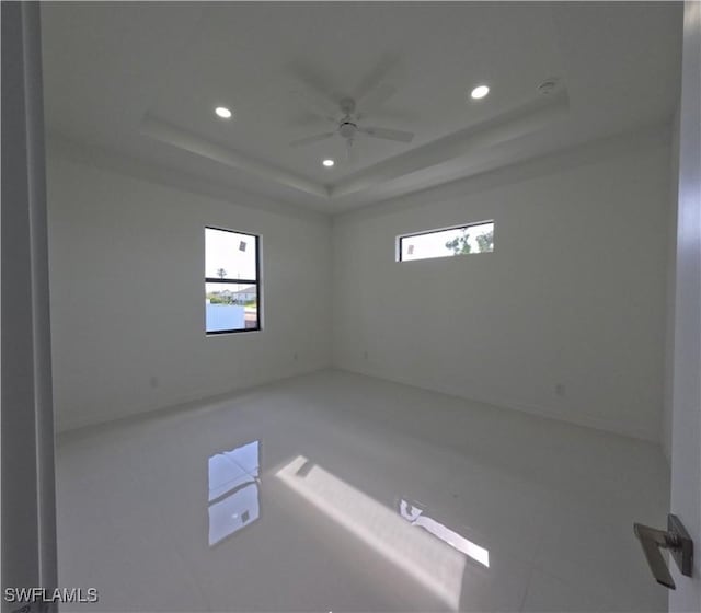 tiled spare room featuring a raised ceiling, plenty of natural light, and recessed lighting