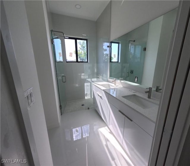 full bath with a sink, a shower stall, and double vanity