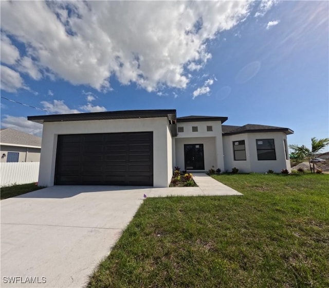 prairie-style home featuring an attached garage, fence, stucco siding, a front lawn, and driveway