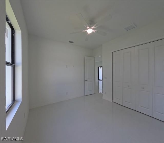 unfurnished bedroom with tile patterned floors, a closet, ceiling fan, and visible vents