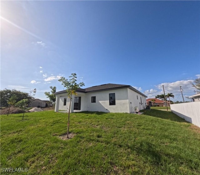 rear view of property with a yard and stucco siding