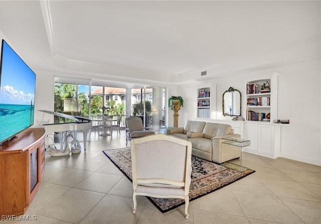 tiled living room featuring a tray ceiling, built in features, and baseboards