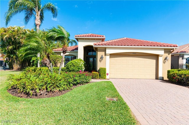 mediterranean / spanish home featuring a front yard, a tile roof, a garage, and stucco siding