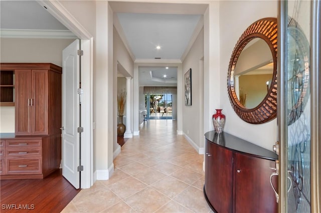 hall with crown molding, light tile patterned floors, and baseboards