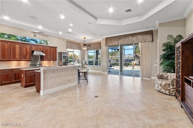 kitchen featuring visible vents, ceiling fan, light countertops, under cabinet range hood, and a center island with sink