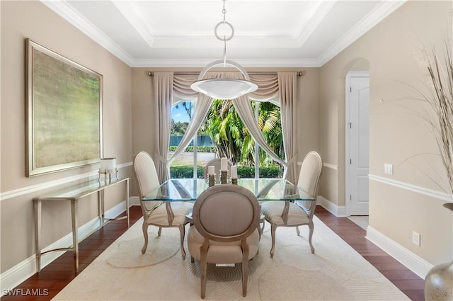 dining space with arched walkways, dark wood-style floors, crown molding, and a raised ceiling