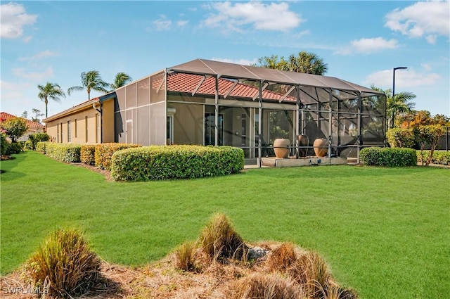 back of property with a yard, stucco siding, and glass enclosure
