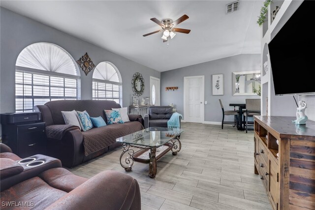 living area featuring baseboards, visible vents, vaulted ceiling, and a ceiling fan