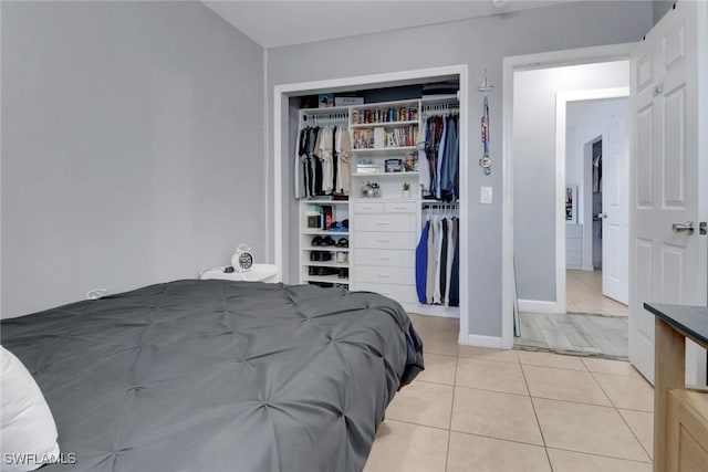 bedroom with a closet, light tile patterned floors, and baseboards