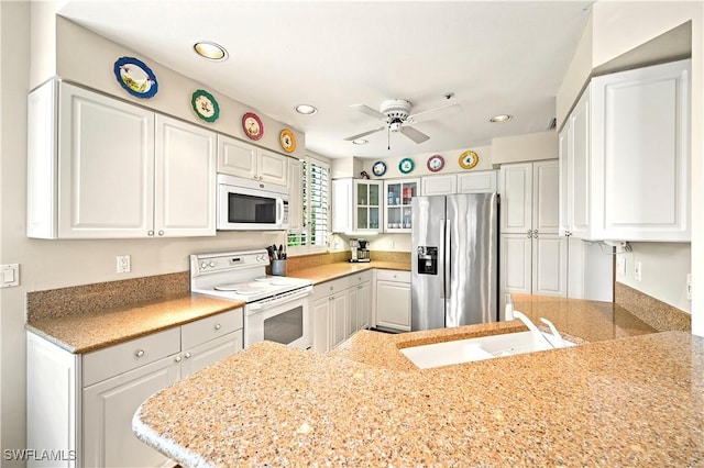 kitchen featuring white appliances, a sink, a ceiling fan, white cabinets, and glass insert cabinets