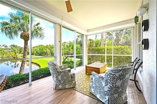 sunroom / solarium with a ceiling fan and a water view