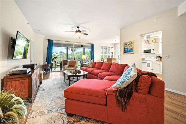 living area with a ceiling fan, wood finished floors, and baseboards