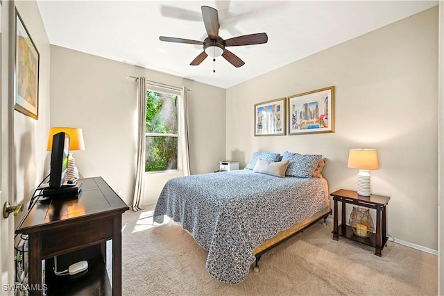 bedroom with light colored carpet, a ceiling fan, and baseboards