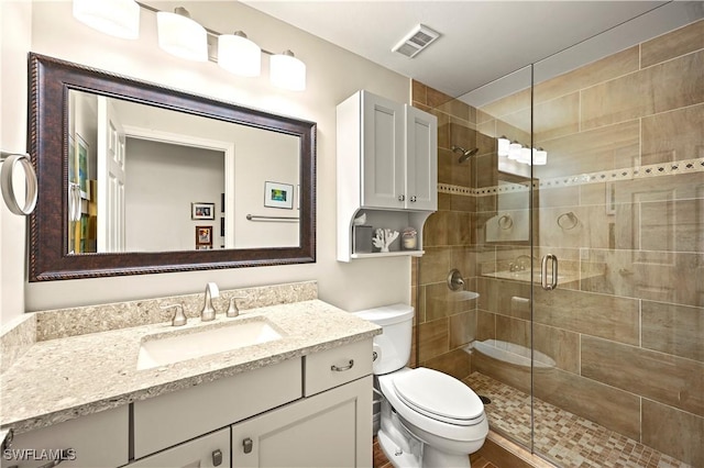 full bathroom featuring a shower stall, toilet, and vanity