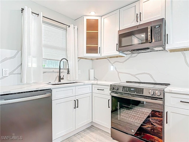 1320 Blue Point Ave Unit 2, Naples, FL 34102 - kitchen featuring appliances with stainless steel finishes, a sink, white cabinetry, glass insert cabinets, and light stone countertops