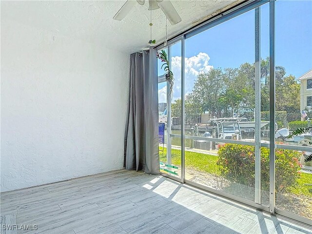 1320 Blue Point Ave Unit 2, Naples, FL 34102 - spare room featuring a textured wall, a ceiling fan, expansive windows, wood finished floors, and a textured ceiling