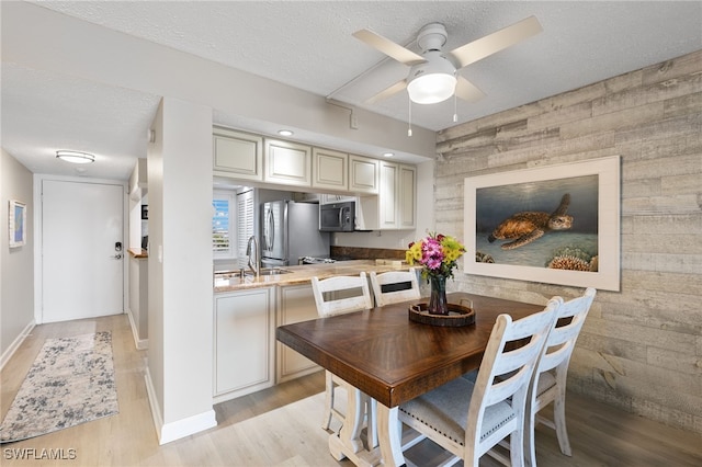 4835 Bonita Beach Rd Unit 407, Bonita Springs, FL 34135 - dining area featuring wood walls, light wood finished floors, an accent wall, and a textured ceiling