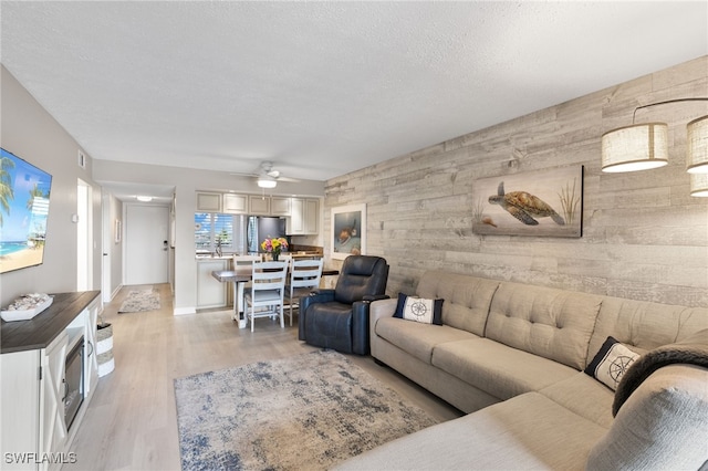 4835 Bonita Beach Rd Unit 407, Bonita Springs, FL 34135 - living room featuring light wood-style flooring, a textured ceiling, wood walls, an accent wall, and ceiling fan