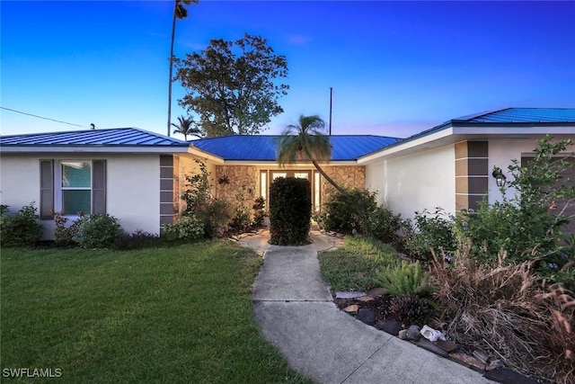 2135 SE 15th St, Cape Coral, FL 33990 - view of front facade featuring a metal roof, stucco siding, a front lawn, and a standing seam roof