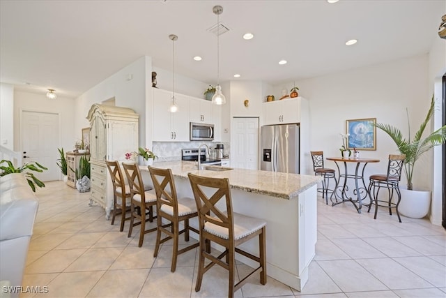 5448 Agostino Way, Ave Maria, FL 34142 - kitchen featuring light stone counters, stainless steel appliances, a peninsula, light tile patterned floors, and a kitchen bar