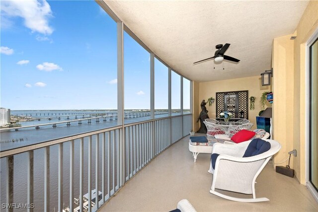 interior space with a textured ceiling, a water view, and a ceiling fan