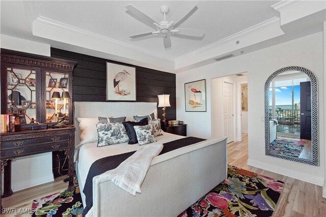 bedroom featuring light wood-style flooring, ceiling fan, visible vents, crown molding, and a raised ceiling
